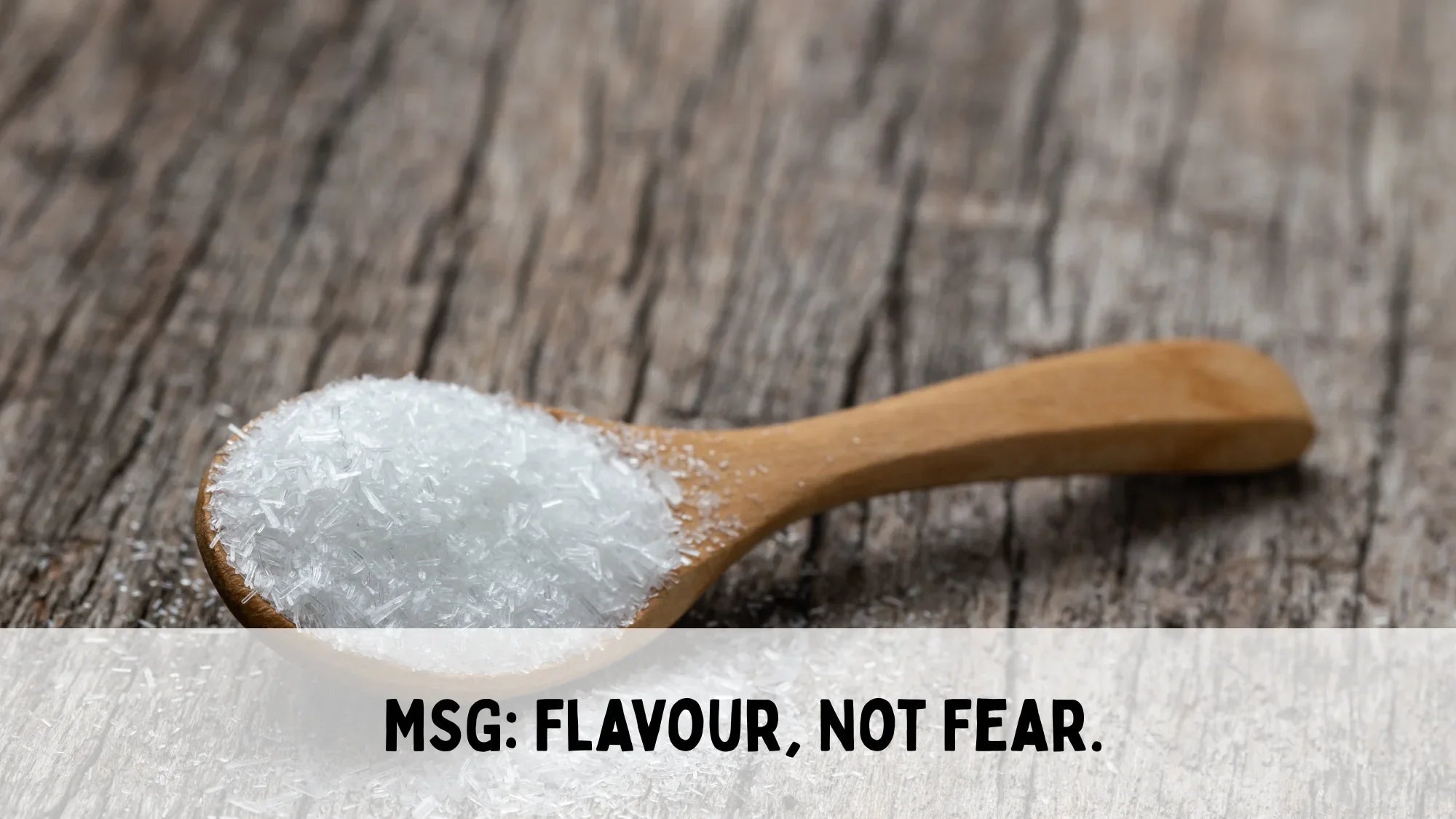 wooden background with a wooden spoon of monosodium glutamate